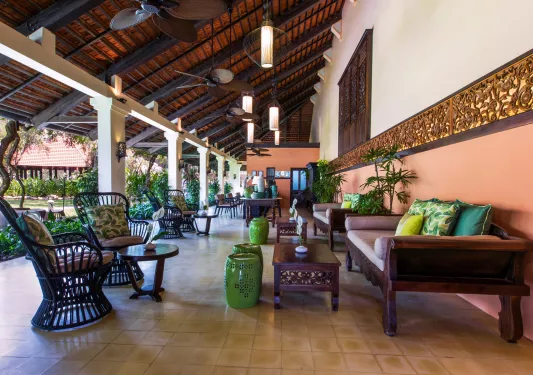 Outdoor patio with cushioned chairs on tile flooring, looking out to a garden