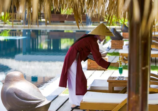 a server brings a drink to the pool