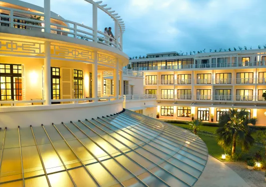 Exterior view of illuminated balconies with two people standing , looking out to other buildings