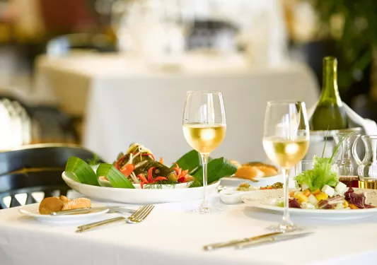 Dining table with two plates of food, and two half empty glasses of white wine