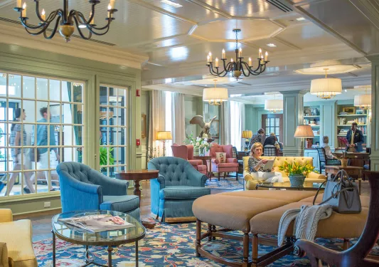 Hotel lobby with large cushioned seats, with people sitting down and reading