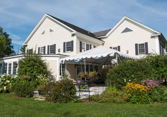 Exterior view of a white building with a grass area with bushes in front