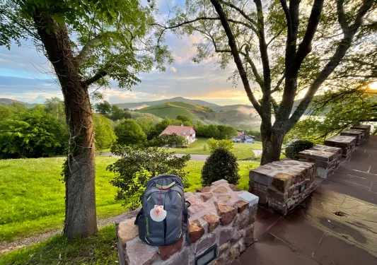 Backpack sitting on a stone block, overlooking a grass valley and small town buildings