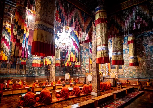 Monks sitting on the ground in the middle of a temply