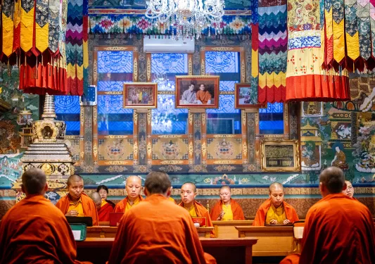 Monks in orange robes sitting inside of a temple