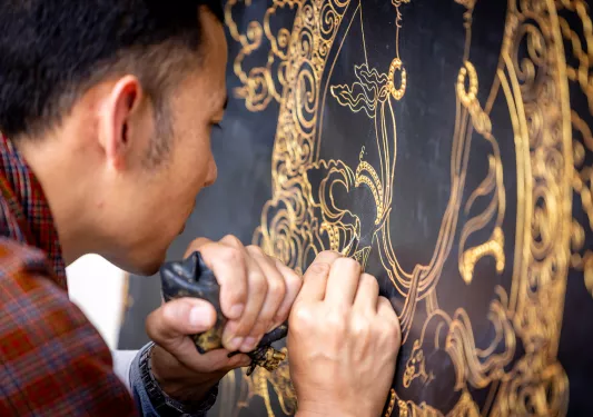 Man making an art piece with a black tool
