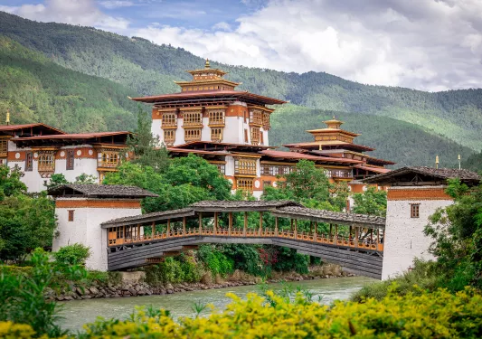 Large white and bronze temple with a wooden bridge below