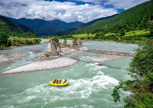 Group of people rafting in a river on a yellow boat
