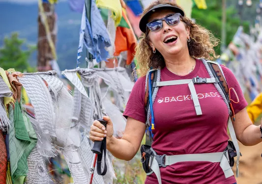 Woman smiling while using walking poles and hiking on a dirt trail