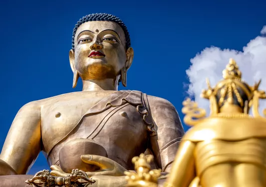Large, bronze statue with blue sky and clouds in the background