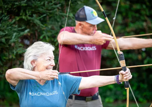 Man and woman smiling with holding a bow and arrow
