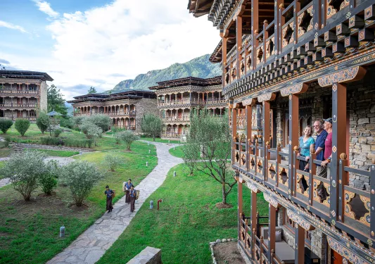 Group of people standing on a wooden balcony with more buildings the background
