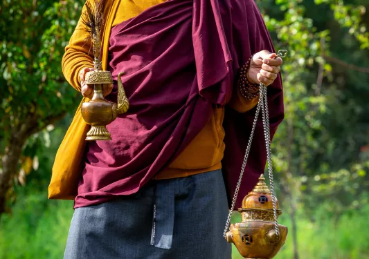 Monk smiling while holding onto bronze items