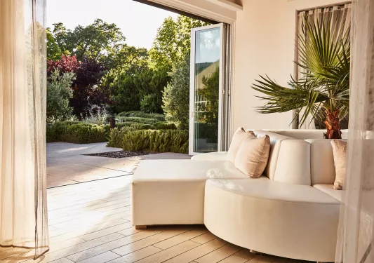 White cushioned couch with open doors leading to a garden
