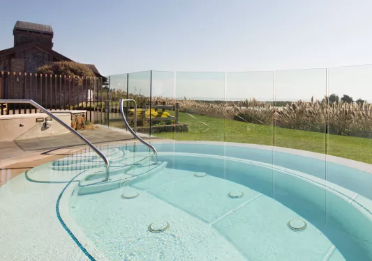 Outdoor pool surrounded by glass walls, looking out to the ocean