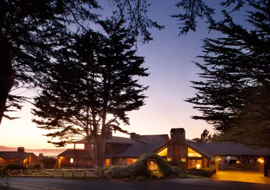 Outdoor view of a hotel entrance, illuminated by orange lights and the sunset