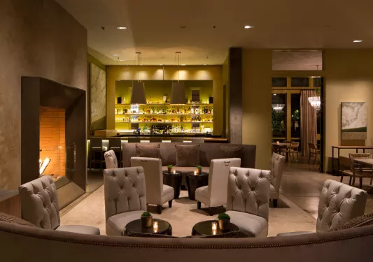 Indoor bar with tall cushioned chairs and a fireplace on the left