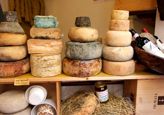 wheels of cheese stacked on a wooden counter