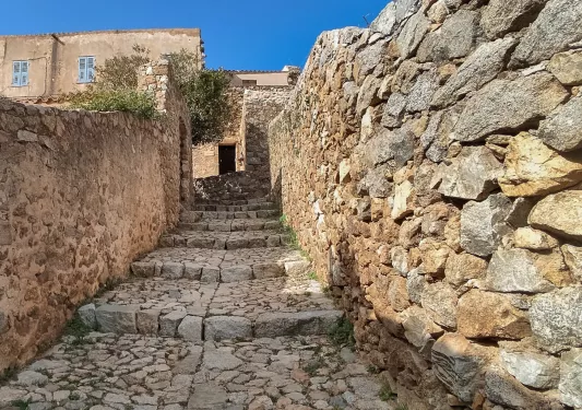 Stone staircase with stone walls leading to brown buildings