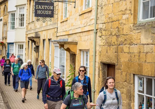 Group of people walking on a stone pathway next to brick buildings