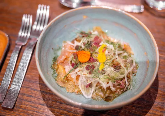 Bowl of food, topped with onions and flower garnishes