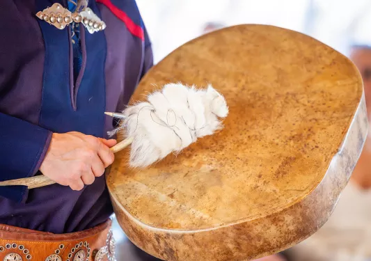Person hitting a drum with a drumstick with a fur point