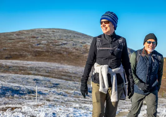 Man and woman wearing sunglasses and smiling in a snowy valley