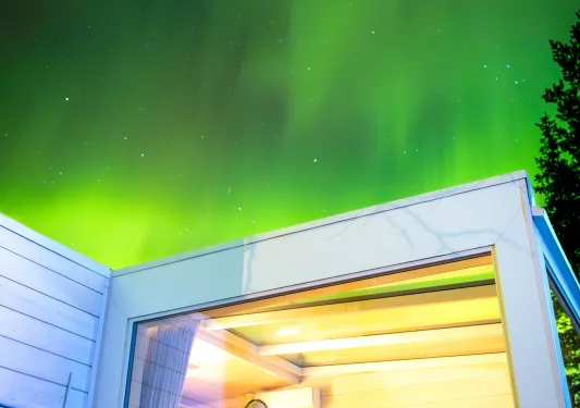 Two women sitting and smile while looking up at and aurora