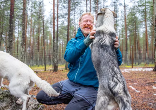 Man smiling while petting two dogs