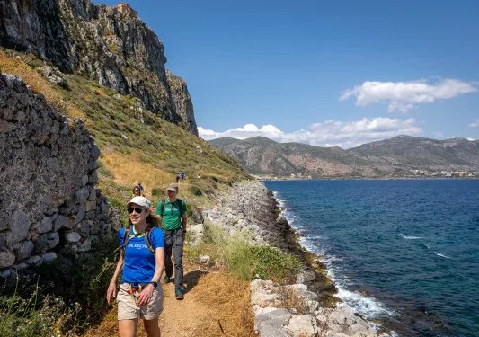 Group of people hiking on a gravel path next to the ocean