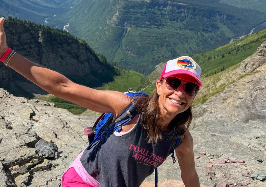 Women with her arms open and smiling on top of a hill