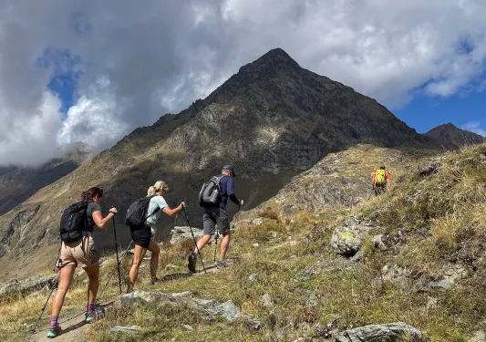 Four people with walking sticks hiking up a mountain
