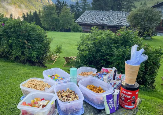 Food containers full of snacks on a rock looking down at a grassy field