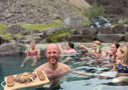Man in a pool holding a cutting board full of cookies