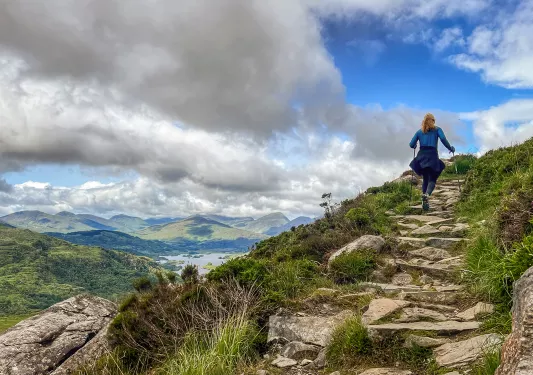 Woman climbing up rock stairs along a hillside