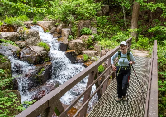 Woman standing on a bridge in front of a waterfall