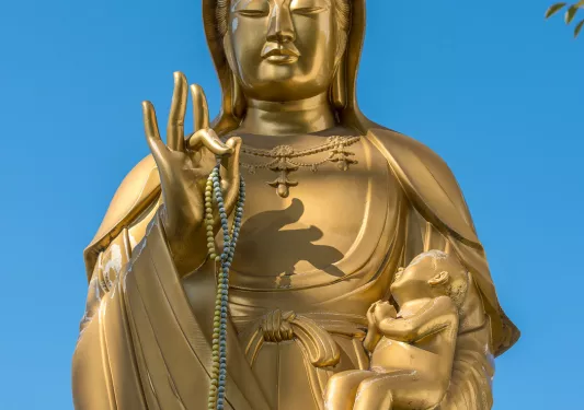 Gold Japanese statue with beads around the hands