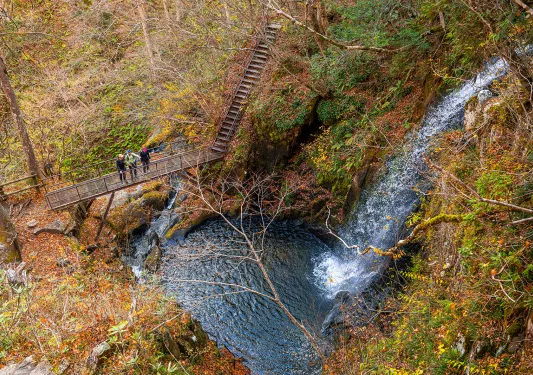 a waterfall falling into a lake, next to a hiking path