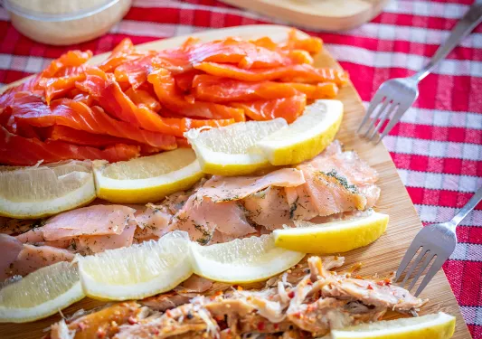 Wooden plank full of cured fish and lemon slices