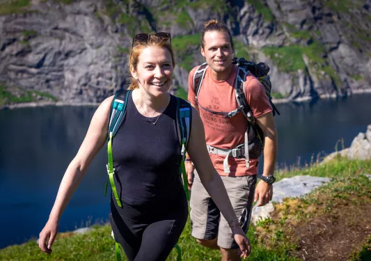 Man and women with backpacks ascending a mountain