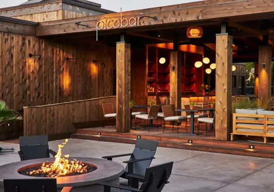 Outdoor bar and lounge with a fire pit and tables with chairs