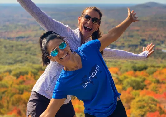 Two women with arms open wide and smiling