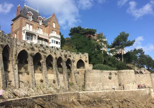 Large house on top of stone castle ruins with a stone pathway on the ground level