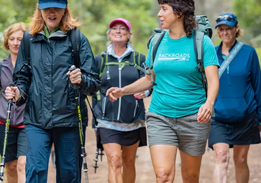 Group of women with walking poles, hiking on a dirt trail