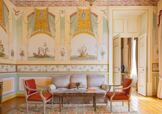 Indoor foyer, with ancient paintings on the walls and cushions chairs in the room