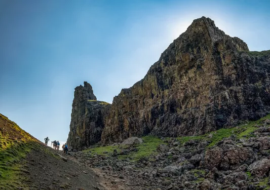 Group of people ascending a hill with a large canyon to the right 