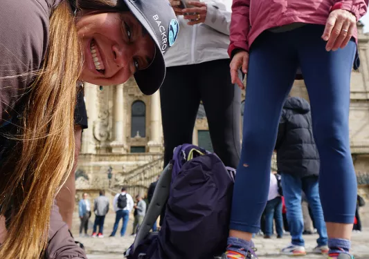 Group of people in a rustic, Spanish town center, huddled over a book with stamps