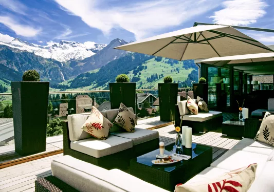 Outdoor patio with green and white furniture, with large mountains in the distance