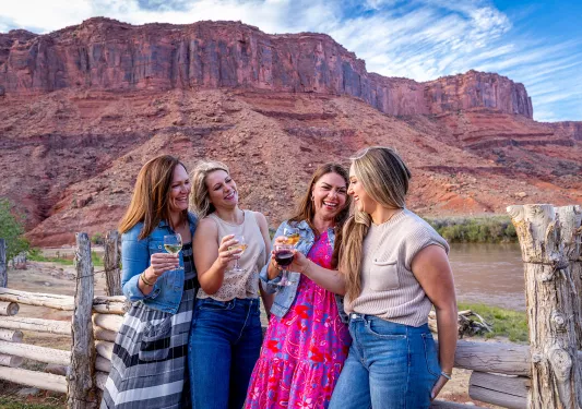 Four women holding wine glasses in front of canyons