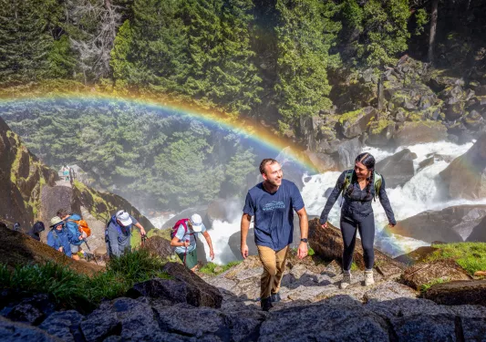 a rainbow behind a group of hikers